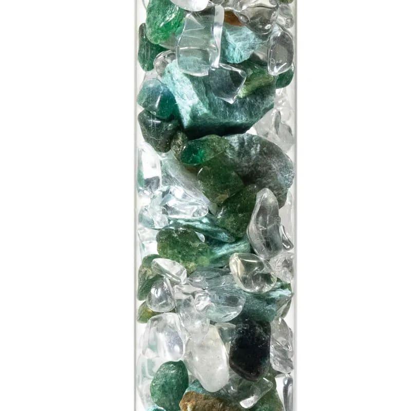 Een glazen fles gevuld met groene en transparante edelstenen en kristallen.