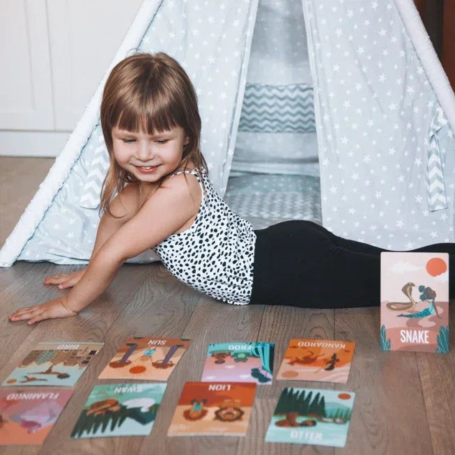 Kind doet yoga cobra pose op houten vloer met dieren yogakaarten voor tipi tent