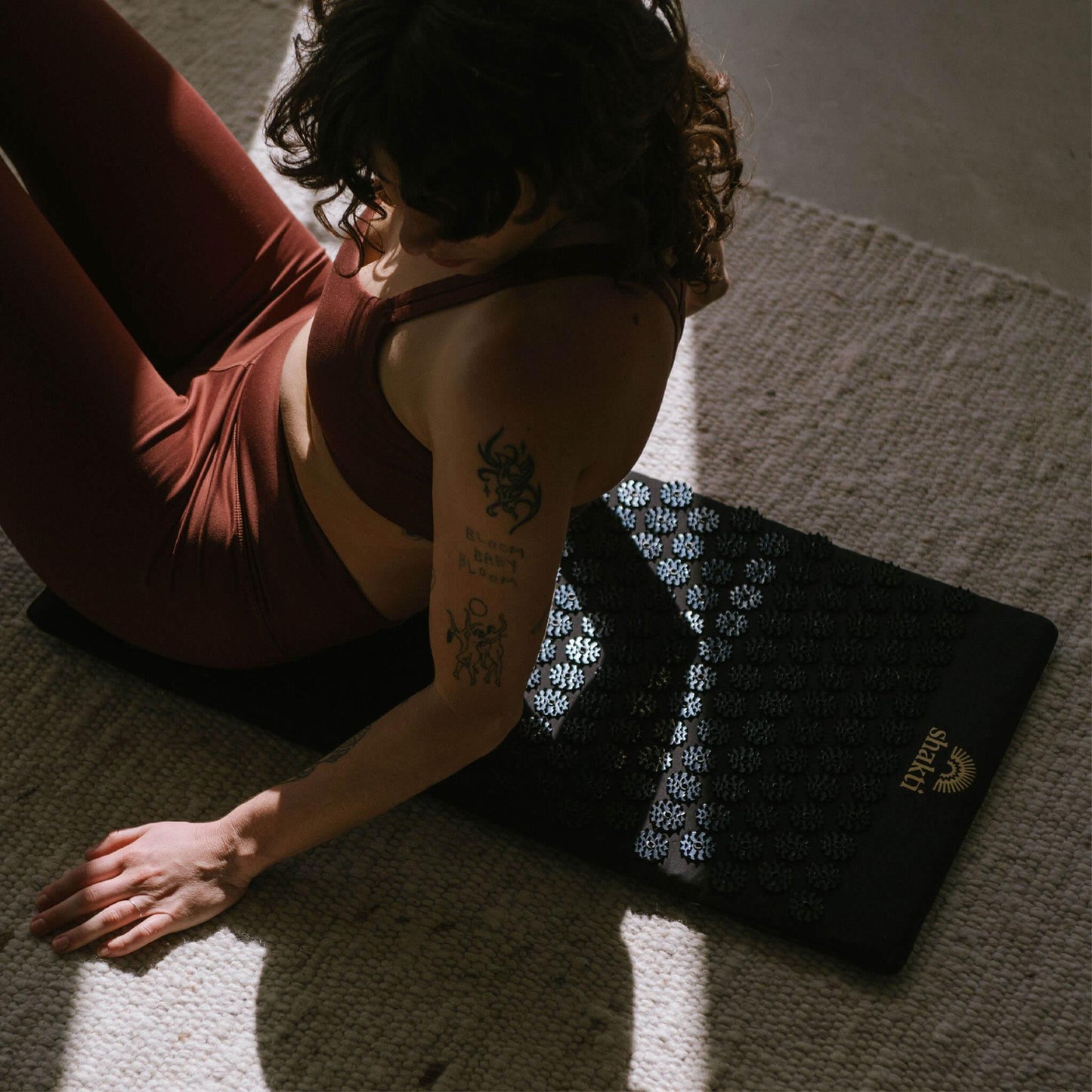 Vrouw ontspant op acupressuurmat voor yoga en zelfzorg, met bloemmotief en zachte textuur