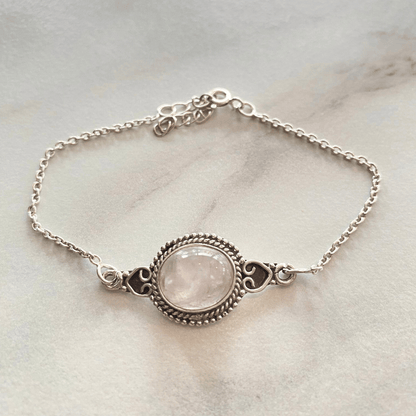 Zilverkleurige armband met een ronde roze kristalsteen en gedetailleerde ornamenten.