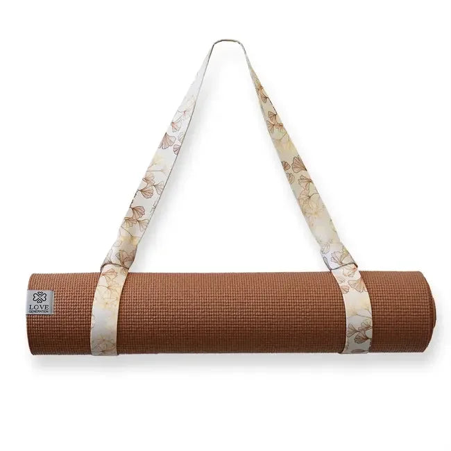 Bruine yogamat met gebloemde draagriem, ideaal voor yoga en meditatie, opgerold