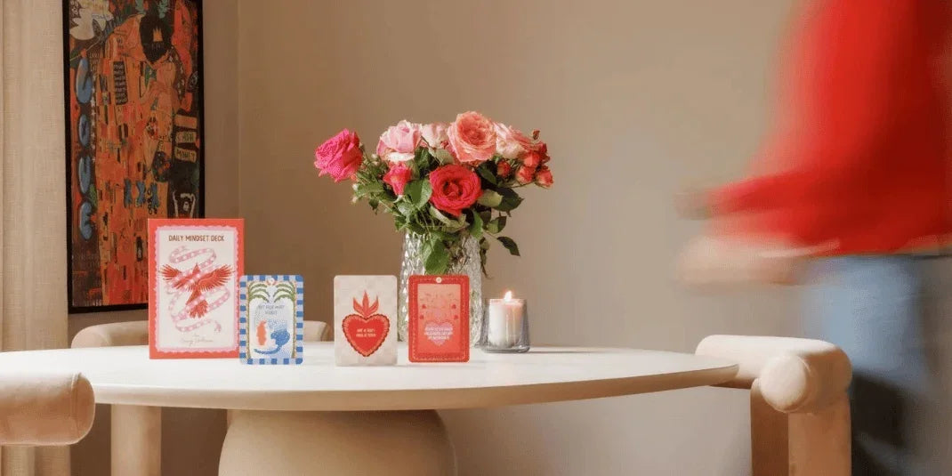 Verschillende mindfulness kaarten en een vaas met roze rozen op een witte tafel.