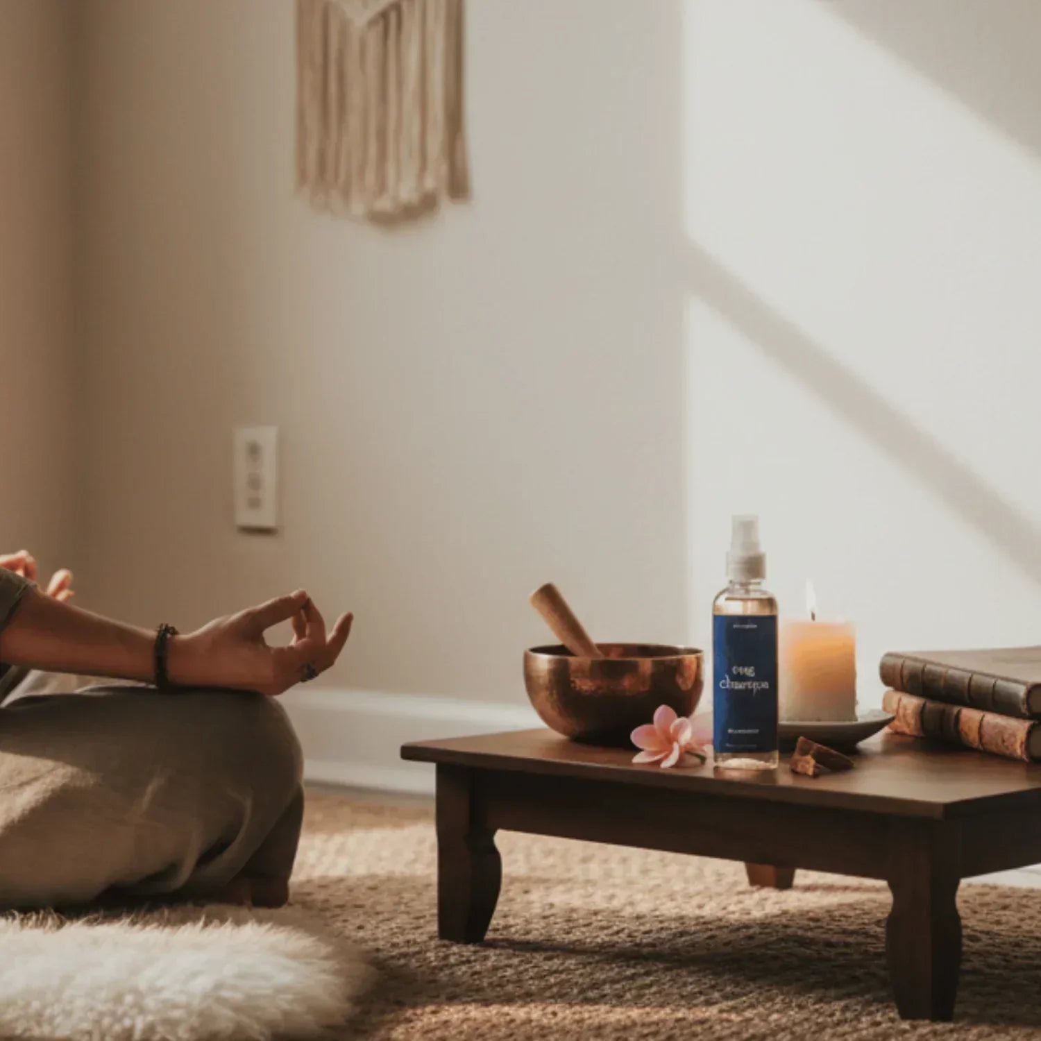 Yoga meditatie hoek met hand in mudra, zangkom, kaars, spray en boeken op tafel