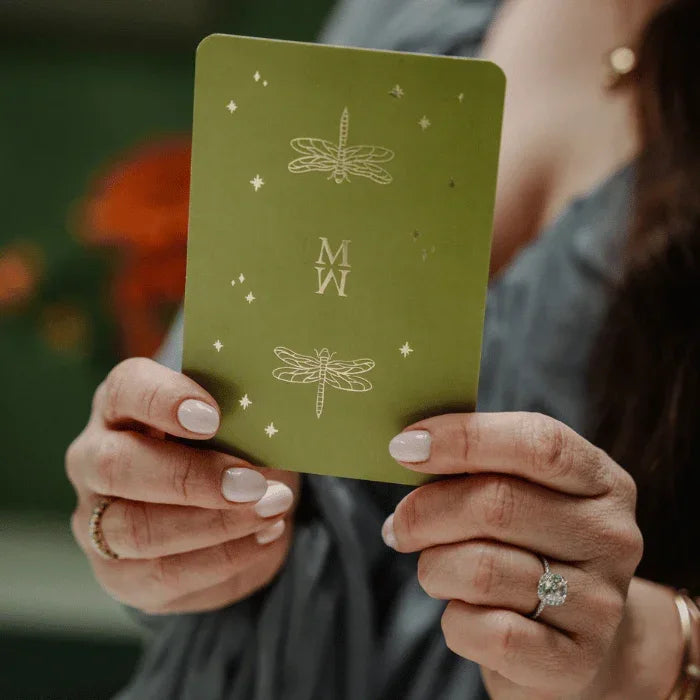 Vrouw houdt groene mindful kaart met libelle en sterren vast, meditatie en selfcare product