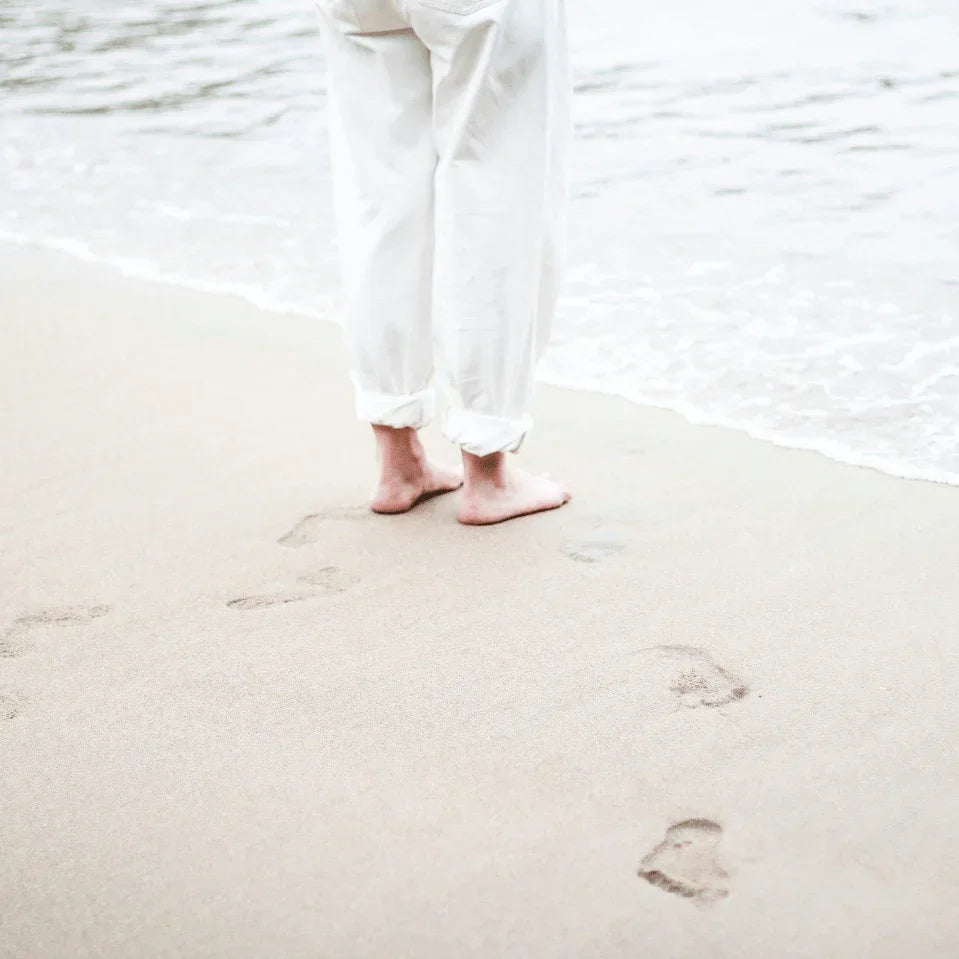 Barefoot op het strand, voetafdrukken in het zand — rust en mindfulness moment
