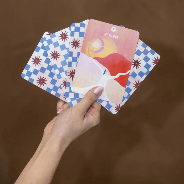 Hand houdt meditatiekaarten met 'Het Keerpunt' en blauw-witte ruitpatroon, voor mindfulness en zelfzorg