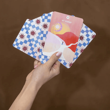 Hand houdt meditatiekaarten met 'Het Keerpunt' en blauw-witte ruitpatroon, voor mindfulness en zelfzorg
